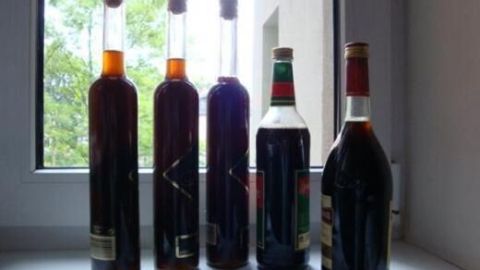 Vier Flaschen Walnusslikör stehen nebeneinander auf einem Tisch, beleuchtet durch das Tageslicht von einem Fenster.