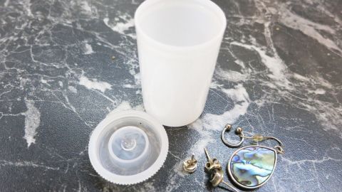 Ein auf einem Tisch liegendes Behältnis mit kaputten Ohringen, bereit zur sicheren Aufbewahrung.