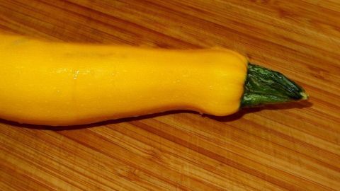 "Zucchinifleisch" würfeln, auf ein geöltes Backblech geben, halbierte Knoblauchzehen und Lauchringe dazu geben, mit Öl begießen (nicht salzen). Im Backofen bei 200 Grad weich, aber nicht matschig werden lassen. Eine gelbe Zucchini liegt auf einem Holzbrett, bereit zur Verarbeitung in verschiedenen Gerichten oder Rezepten.