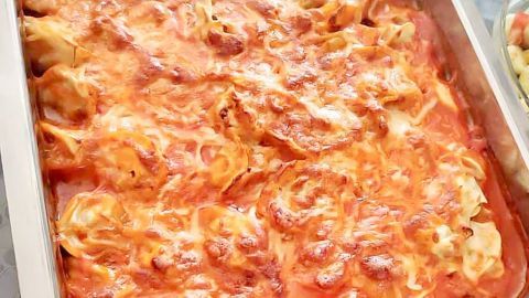 Ein großer Auflauf aus Maultaschen in einer silbernen Form, gebacken in roter Sauce und schmelzendem Käse.