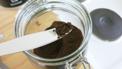 Eine schöne Farbe für braune Soßen erhält man, wenn 1-2 Messerspitzen Kaffeepulver dazugegeben werden. Ein Löffel mit frischem Kaffeepulver wird aus einem Glasbehälter gehoben, um eine braune Soße zuzubereiten.