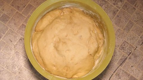 Ein Hefeteig in einer gelben Schüssel geht auf und zeigt eine weiche, luftige Konsistenz auf einer Küchentheke.