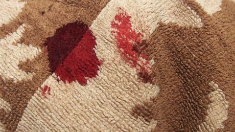 Spucke gegen Blutflecken: Klappt immer, habe es auf Stickereien ausprobiert, denn Spucke ist immer zur Hand. Rote Flecken sind auf einem braunen, gemusterten Stoff zu sehen, was auf Blutflecken hinweist, die gereinigt werden müssen.