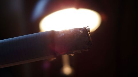 Eine Zigarette glimmt in der Nähe einer Lampe, während sie ohne Feuerzeug oder Streichhölzer angezündet wird.