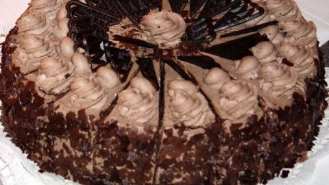 Eine köstliche Schokotorte steht auf einem weißen Tisch, umgeben von einer warmen, orangefarbenen Wand.