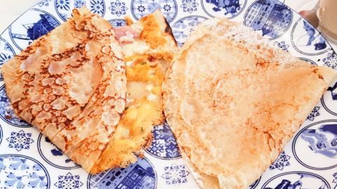 Auf einem blauen, dekorativen Teller liegen zwei aufgeklappte Pfannkuchenpizza-Stücke, die lecker und knusprig wirken.