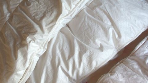 Eine weiße Bettdecke liegt ordentlich auf einem Bett und zeigt eine glatte Oberfläche im Schlafzimmer.