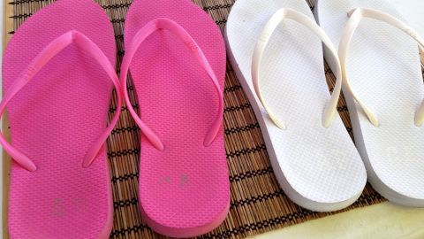 Rosa und weiße Flip-Flops liegen nebeneinander auf einem Tisch, bereit, mit Gardinenwaschmittel gereinigt zu werden.