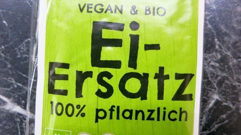 Ein Paket mit grünem Etikett zeigt "Ei-Ersatz" und betont, dass es 100% pflanzlich und vegan ist.