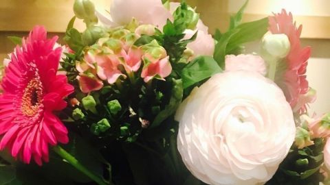Ein schöner Strauß aus bunten Blumen steht in einer eleganten Vase auf einem Holztisch und strahlt Frische aus.
