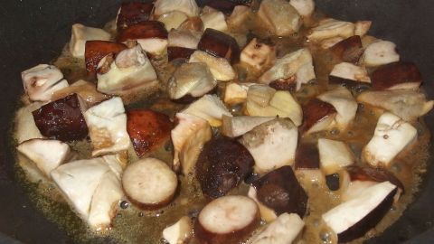 Gebackene Pilze in einer Pfanne mit Olivenöl, die goldbraun braten und appetitlich in einer modernen Küche angerichtet sind.