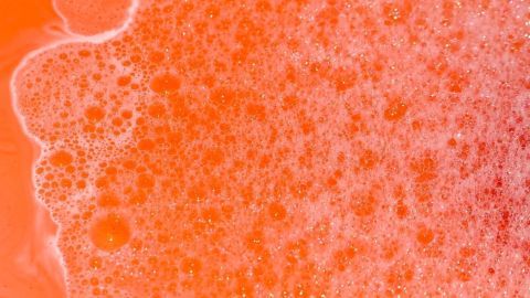 Oranges, schäumendes Badewasser sprudelt, bedeckt mit vielen kleinen Blasen, und füllt einen bunten Badebereich aus.