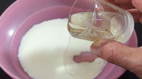 Ein Glas Flüssigkeit wird in eine Schüssel mit Sahneersatz gegossen, um eine gesündere Zubereitung zu fördern.