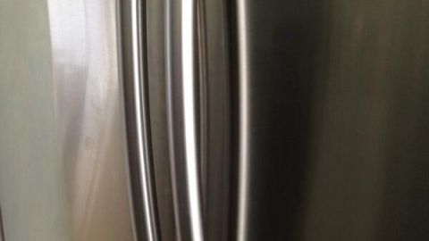 Edelstahlkühlschrank zeigt seinen glänzenden Türgriff in einer modernen Küche ohne sichtbare Verschmutzungen.