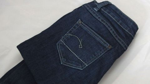 Dunkelblaue Jeans liegen gefaltet auf einer hellen Oberfläche, bereit, die Jeansfarbe aufzufrischen.