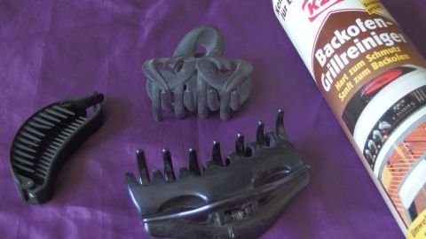 Einfach Backofenspray auf die Spangen aufsprühen, einwirken lassen und wieder abspülen. Alles ist sauber und hygienisch rein! Haarspangen liegen auf einem lila Untergrund, während Backofenspray daneben steht, bereit zum Reinigen der Spangen.