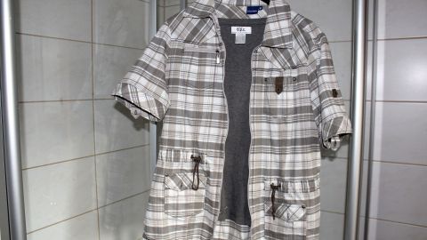 Eine kariert Hängemantel hängt an einem Haken in einem Badezimmer, bereit, nach dem Waschen „schleudertrocken“ zu werden.