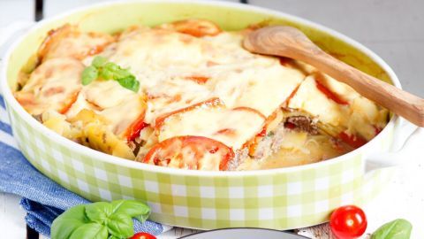 Ein herzhaftes Hackfleisch-Kartoffel-Auflauf wird serviert, während er in einer grün-weiß karierten Auflaufform dampft.