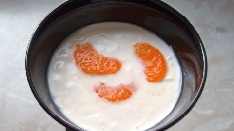 Eine Schüssel Quarkspeise mit Mandarinenstücken zeigt eine cremige Mischung, die in einem modernen Küchenumfeld präsentiert wird.