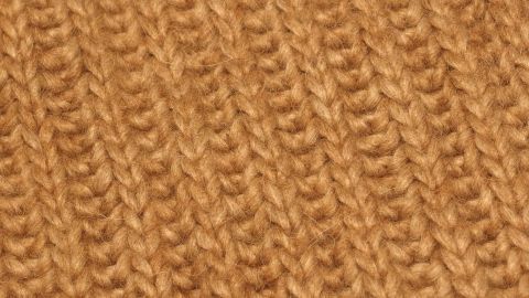 Ein weiches, goldbraunes Strickmaterial liegt auf einer Fläche, bereit zum Waschen empfindlicher Kleidung.