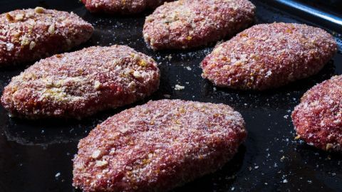 Runde Chilifrikadellen liegen auf einem Backblech, bereit zum Braten in einer Küche, mit einer leicht gewürzten Oberfläche.
