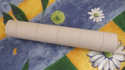 Kostenloses Spielzeug für Kleintiere: Mit Möhren oder anderem Futter gefüllte Papierrollen. (Z. B. Toilettenpapier-, Küchenpapier- oder Geschenkpapierrollen). Ein heller, runder Rollenspielzeug liegt auf einer bunten Decke, ideal für Kleintiere zum Spielen und Nagen.