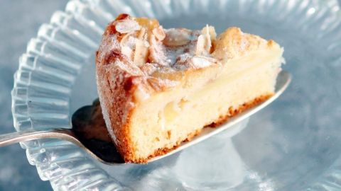 Saftiger Apfelkuchen mit Mandeln wird auf einem eleganten Glasplatten serviert, mit einem Stück auf einem Löffel.