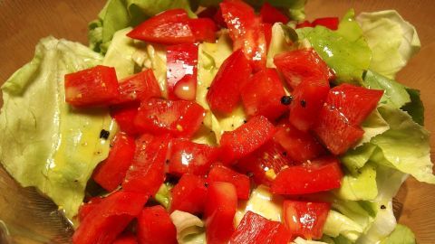 Frischer gemischter Salat mit grünen Blättern und roten Tomatenstücken, bereit für ein schnelles Dressing.