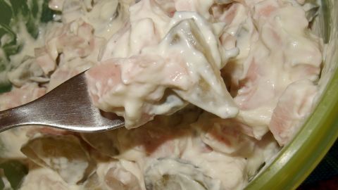 Eine Schale mit selbstgemachtem, nicht so fettigem Fleischsalat wird mit einer Gabel serviert. Der Salat sieht cremig aus.