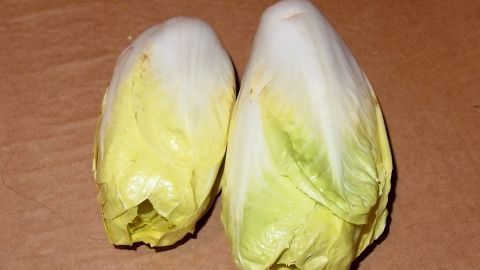Zwei Köpfe Chicoree liegen auf einer braunen Unterlage, frisch und bereit zum Braten als köstliches Gemüsegericht.