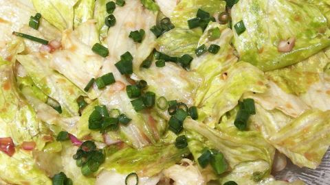 Frischer Salat ist mit einer klassischen Sauce Vinaigrette und gehackten Frühlingszwiebeln angerichtet.