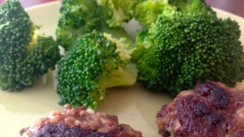 Frischer Brokkoli liegt knackig auf einem Teller, umgeben von gegrilltem Fleisch, bereit zum Verzehr.