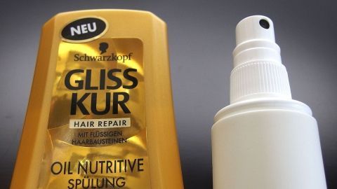 Eine goldene Flasche mit Haarpflegeprodukt steht neben einem weißen Sprühfläschchen, beide für schnelles Leave-in-Haarpflege.