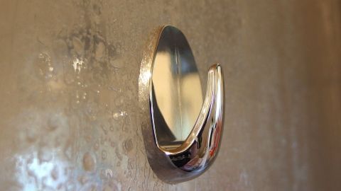 Ein klebender Haken hängt an einer feuchten Wand, während er darauf wartet, dass etwas daran aufgehängt wird.