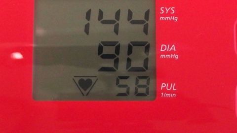Bei Bluthochdruck sollte man auf den Verzehr von Lakritze verzichten. Ein Blutdruckmessgerät zeigt Werte von 144 (SYS) und 90 (DIA), was auf Bluthochdruck hinweist.