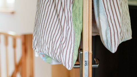 Kissen hängen an einem Holzgestell, während frische Luft in den kleinen Raum strömt, um die Betten zu lüften.