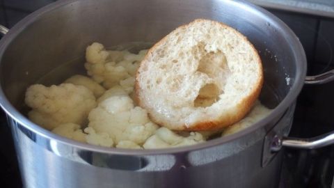 Im Topf kocht Blumenkohl, während ein Stück Brot darin schwimmt, um unangenehme Gerüche zu vermeiden.