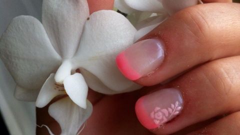 Eine Hand mit gepflegten Nägeln hält zarte weiße Orchideenblüten, die sanft in der Umgebung leuchten.