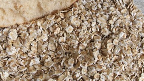 Alternative zu altbackenen Weißmehlbrötchen für Hackfleischteige sind Haferflocken. Haferflocken liegen verstreut auf einer Arbeitsfläche, während sie zur Zubereitung von Hackfleischteig verwendet werden.