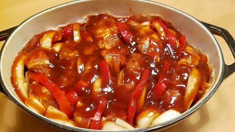 Ein herzhaftes Schichtgulasch mit zarten Fleischstücken und buntem Gemüse in einer leckeren Sauce, serviert in einer Auflaufform.