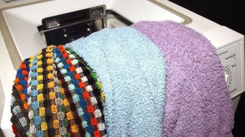 Bunte Handtücher werden in eine Waschmaschine gelegt, um sie im Rahmen des Waschens und Sortierens zu reinigen.