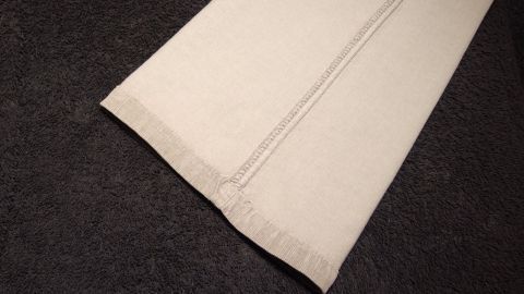 Mithilfe von Sprühstärke halten Bügelfalten von Hosen länger. Ein Hosenbein mit klaren Bügelfalten liegt auf einem dunklen Hintergrund und zeigt die scharfen Materialien und Nähte.