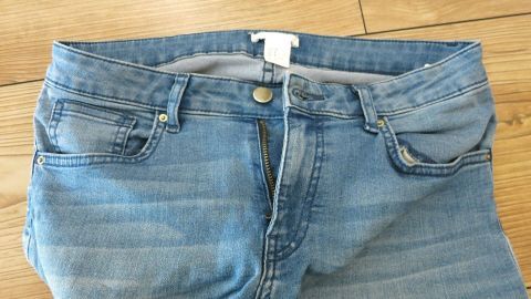 Jeans ohne geschlossenem Reißverschluss und Knopf auf Holzboden liegend, zeigen das Zwei-Knopf-System nach dem Essen.