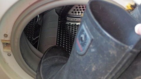 Schwarze Gummistiefel werden in die Waschmaschine gesteckt, um sie gründlich zu reinigen und vom Schmutz zu befreien.