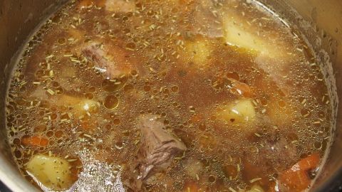 Eine köstliche Fleischsuppe kocht in einem Topf, mit zarten Fleischstücken und Gemüse in einer wohligen Brühe.