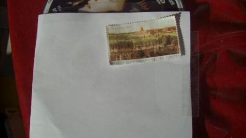 Ein Umschlag mit einer Briefmarke liegt auf einer DVD-Hülle. Die Briefmarke zeigt ein historisches Gebäude.