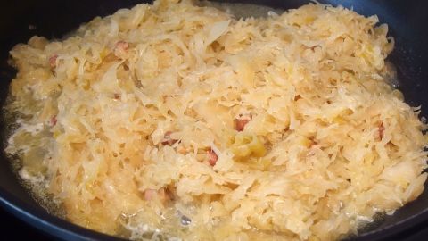 In einer Pfanne schmort Sauerkraut, goldbraun und weich, um ein köstliches Gericht zuzubereiten und die Reinigung zu erleichtern.