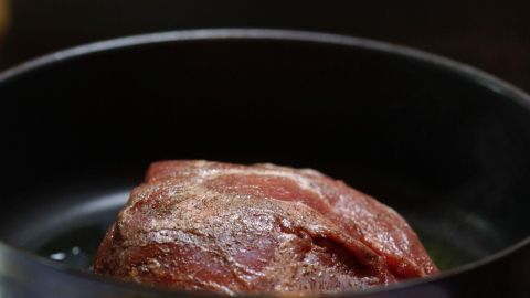 Rinderbraten vor dem Anbraten in kochendes Wasser tauchen, so wird das Fleisch saftiger und zarter. Ein saftiger Rinderbraten liegt in einem Topf, während er auf dem Herd gart und eine appetitliche Bräunung annimmt.