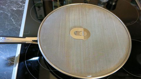 Ein Bratgitter liegt auf einem modernen Kochfeld und schützt vor Spritzern beim Kochen, während es gleichzeitig hitzebeständig ist.