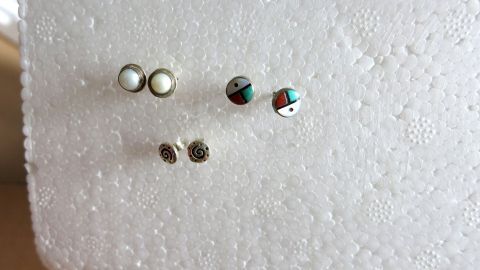 Bewahre Deine Ohrstecker praktisch auf, indem Du ein Stück Styropor benutzt. Es hält die Ohrstecker sicher an Ort und Stelle und sorgt dafür, dass sie nicht verloren gehen. Ideal für Ordnung und Übersichtlichkeit. Ohrstecker stecken in Styroporplatte zur Aufbewahrung. Der Hintergrund ist neutral und der Fokus liegt auf den Ohrsteckern.